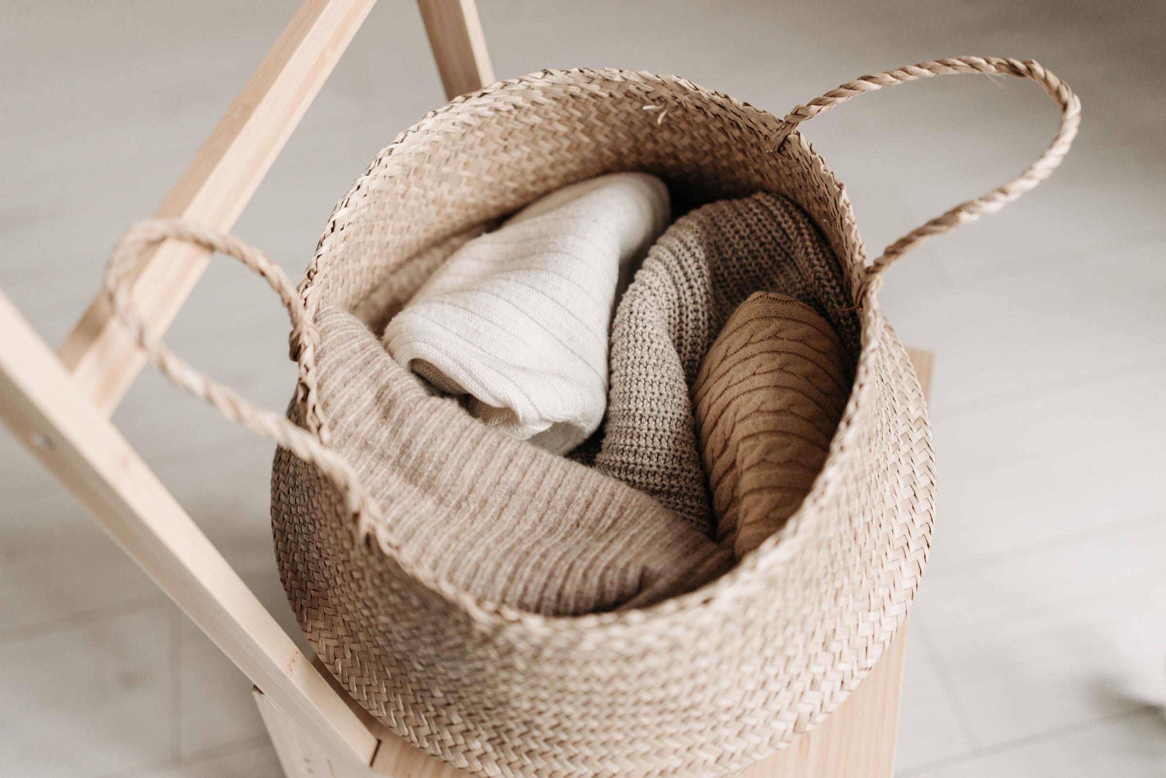 A woven laundry basket with neatly rolled, freshly cleaned knitwear